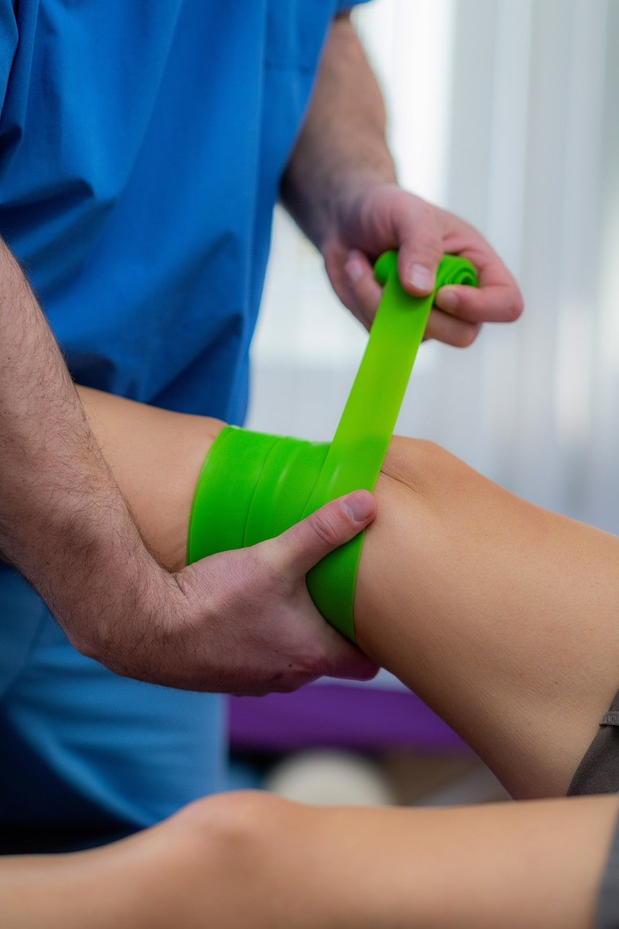 Person applying green compression tape to a person's leg